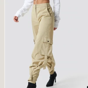 Cargo pants, Ivana Santacruz x Nakd - Superbekväma och snygga beiga cargo byxor från Nakd x Ivana Santacruz. Dom går att knäppa nere vid ankeln eller så kan man låta dom vara vida där nere😍 