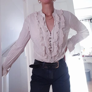 Volang-blus - En jättevacker blus med volanger och fina detaljer. Knappar så ärmen går att knäppa men kan även vikas upp som en skjorta.💙 Blusen är storlek L men sitter så som den gör på bilderna på mig som är storlek S.