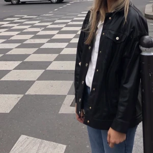 Tunn skinnjacka (fake) från Zara, strl S - Perfekta ”jackan” att ha till fest. Funkar även att ha på våren/hösten som jacka, men även på vintern under en tjockare jacka. Fake-skinn från zara med silverknappar. Strl S!!