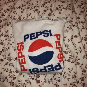  - En pepsi hoodie från h&m i vit färg som är något croppad.