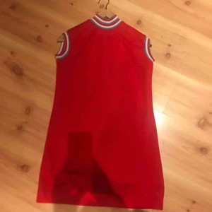  - Söt klänning i 60-tals anda! Polyester, klarröd med randiga detaljer. Ingen storlekslapp men gissar på en s-m!
