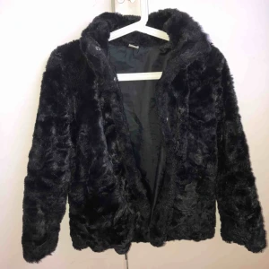  - Väldigt fin pälsjacka perfekt till höst och vintern. Svart väldogt skön att ha på sig och mysig. Barnstorlek 146. Knäpps med knappar och har liten krage 