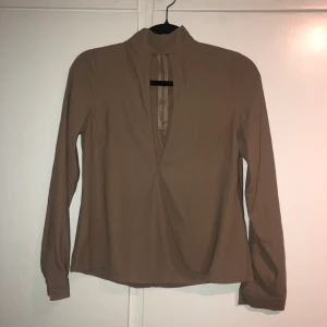 Topp från NA-KD strl 34 - Urringning i mitten av tröjan. Brösten syns ej, mer som en detalj. Tröjan är lite ljusare i verkligheten. Använt någon gång.