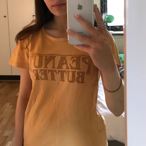 Mörkgul t-shirt - En mörkgul t-shirt som det står ”peanut butter” på, från Bikbok, i storlek S🌻 Frakt tillkommer senare💕💖
