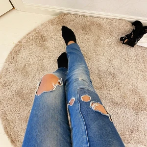 Slitna jeans med detaljer  - 266kr inklusive frakt. Ett par  slitna slim jeans med detalj på ena låret som har en rektangel i en mörkare blå färg. De är lågmidjade. Jag är 163cm💛 storlek 26/32!  Säljs pga jag har för många byxor  Fråga mig om du har några funderingar 💛☺️ 