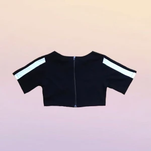 Kort topp - Kort topp med vita ränder på sidan och dragkedja bak. Väldigt sportig! Storlek XS med prislapp kvar så aldrig använd. Frakt inräknat i priset!