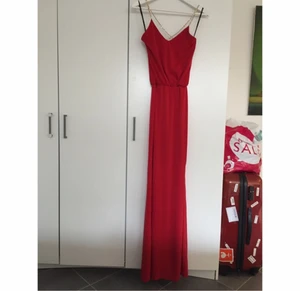  - Snygg vinröd maxiklänning med djup V-ringning i ryggen. Strass band. Oanvänd.