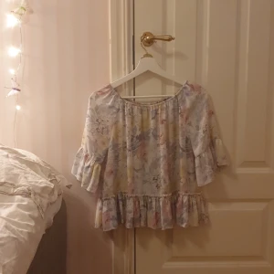 Blommig off-sholder top - Superfin blommig off-shoulder top från Bik bok. Trekvartsarm. Volamgdetaljer. Använd fåtal gånger och inga defekter eller fläckar💕. Frakt tillkommer!!