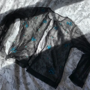 Blus i mesh med broderade blommor - Jättefin blus/topp i tunt mesh-tyg med broderade blommor. Knäppa med små knäppen. Passar XS-L beroende på hur man vill att den ska sitta. Liknar de trendiga tröjorna från zara med broderade blommor. Fri frakt!