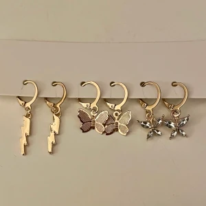 3 par guldiga örhängen - 3 par guldiga örhängen, fjärilar och blixtar! Säljes då dem aldrig kommit till användning. Frakt tillkommer!💞 Säljer helst alla 3 par samtidigt (då för 110kr inkl frakt, annars 50+frakt)💞