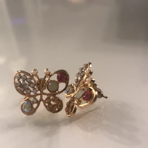 Örhängen  - Ett par örhängen som är formade som fjärilar med superfina färger och stenar på som aldrig lyckats blivit använda 