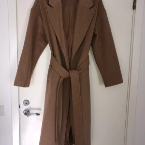 Gina tricot beige kappa  premium collection  - Beige kappa från Gina tricots premium collection i storlek 38. Använd en handfull gånger så i nyskick! Hämtas i Stockholm eller leverans mot fraktkostnad.  