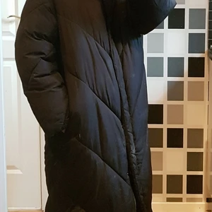 Puffer, Monki, vinterjacka, kappa - Lång puffar från Monki. Har hängt sig i nedersta dragkedjan men det är lätt fixat. Den går att stänga helt. 