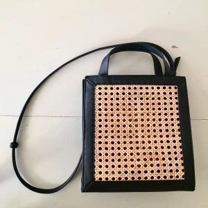 Svart rotting väska retro  - En supervacker svart väska i rotting. Avtagbart band som gör att den kan användas på två sätt. 25x27 cm. I nyskick. 