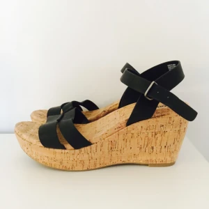  - Helt nya kilklacksskor, US 8 1/2, strl 39.
Klackhöjd ca 6-7cm. Reglerbara svarta band. 