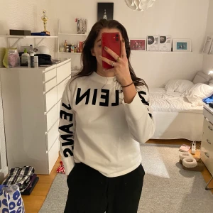Sweatshirt  - Vit sweatshirt (halvt polo) med tryck ”CALVIN KLEIN JEANS” över armarna och bröstet. Tvivlar på att den finns kvar då jag haft den ett tag men har knappt använt den och den är i fint skick. Storlek S men är själv en M så passar även M.