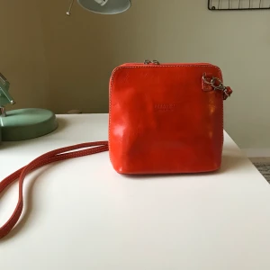 Orange handväska - Köpte denna på second hand för ett tag sedan men den är i perfekt skick. Hittade kvitton i den från Italien så den har i alla fall varit någon gång i sitt liv i Italien🇮🇹 frakt på 66 kr tillkommer