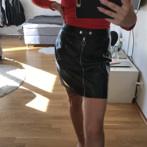  - Tightare kjol i blank läderimitation. Dragkedja och knappar. Använd endast en gång! Frakt ingår i priset 