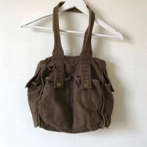  - Brun mellanstor axelväska i denim-tyg med många fack och fickor. Bruksskick, men en väska med kvar att ge!  Kan mötas i Stockholm eller skicka mot fraktkostnad! ✨🌸✨