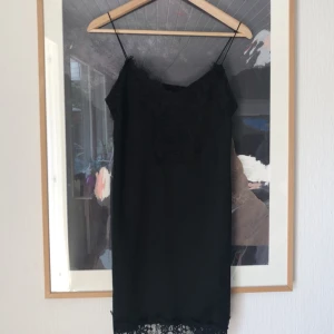  - Snygg svart klänning med spetsdetaljer! Har nopprat sig lite (kan ses på tredje bilden), då jag råkade gå in i ett staket :-)  Möts ej upp, skickar endast, men frakten ingår i priset!