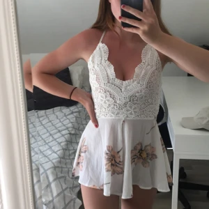  - Extremt vacker jumpsuit. Det är vit med spets och aprikos färgade blommor på. Sitter ursnyggt på och passar perfekt nu till sommaren. Bekväm och sval :)