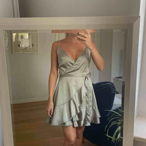  - Metallic-grön/grå volangkläning med justerbaraband, dragkedja där bak & knytbart band i midjan. Köpt från Boohoo i storlek UK8, vilket motsvarar storlek 36. Aldrig använd. Frakt ingår!