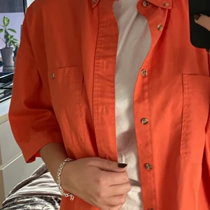 En kortarmad skjorta strl L - En snygg orange/rosa skjorta, bra skick och sitter luftigt och bra! 