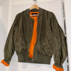 Grön bomberjacka - Grön bomberjacka med texten ”waste no time” på baksidan. köpt för ungefär 3 år sedan men använd bara 2 gånger, köparen står för frakten