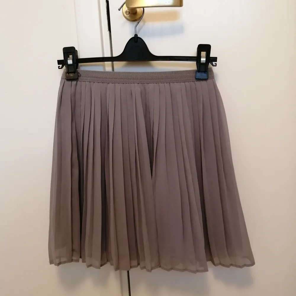 Gullig, kort kjol i en ljusgrå färg. Från Uniqlo, stl xs. Elastisk runt midjan och två lager. 100% polyester. . Kjolar.