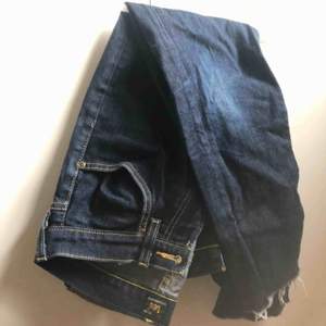 Ett par mörkblåa lee-jeans. Köpta secondhand så är lite osäker på storleken. Jeansen är avklippta och avslutas ungefär vid ankeln 