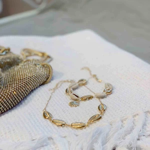  - Fint halsband med guldiga snäckor! Finns även en matchande fotlänk/alternativt armband. Ett för 55kr eller båda för 90kr. Frakt tillkommer på 9kr. 