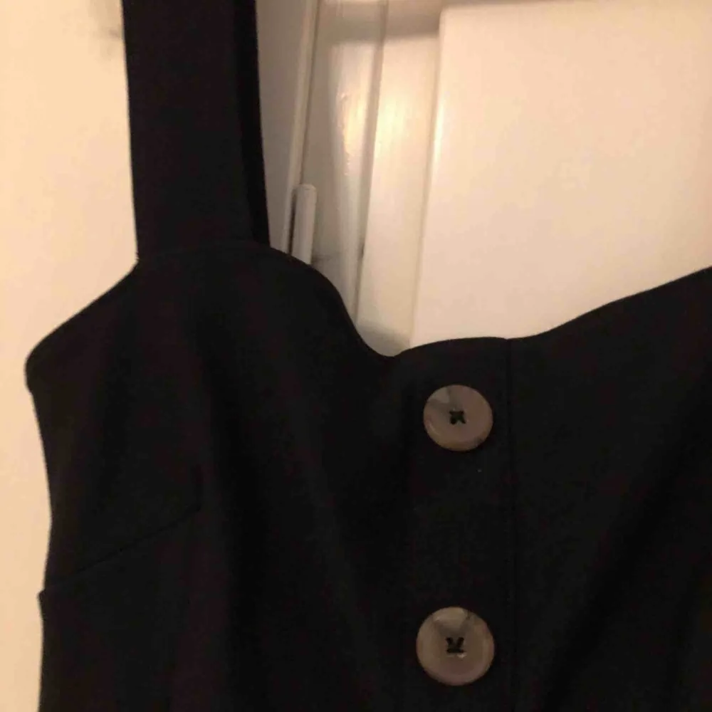Svart klänning med knappar i lyxigt material från Urban Outfitters  Stl XS/S. Klänningar.