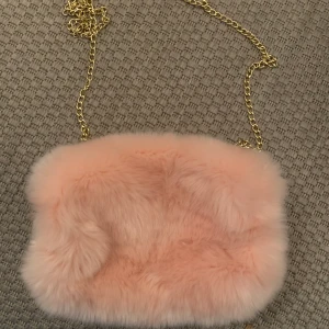 Handvärmare i fuskpäls - Säljer den här handvärmaren i rosa fuskpäls. Insidan är av fleece. Man kan ta bort kedjan. Perfekt att han istället för vantar. Endast använd 2 gånger. 