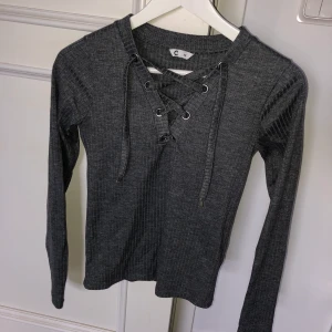Kabelstickad tröja - Kabelstickad mörkgrå tröja från Cubus i strl XS. Justerbar snörning i fram. Knappt använd