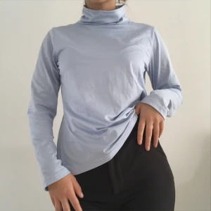 Ljusblå Oversize Polotröja - 🌍Frakt ingår i priset!🌏 Fin tröja med hög krage i glansigt material. Jag är XS och såhär sitter den på mig. Står EU 40 i den, så passar alla storlekar beroende på hur du vill att den ska sitta.