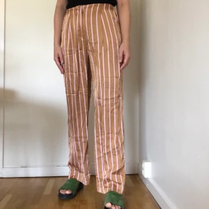 2NDDAY silkesbyxor - Randiga silkesbyxor från 2NDDAY. Storlek 36. Lös modell. Högmidjade. Guldbruna med rosa/vit rand.