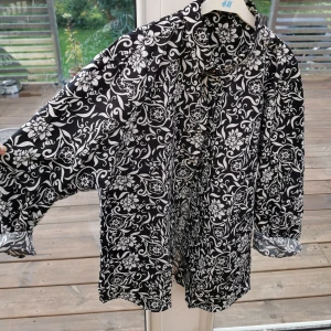 Fin skjorta, helt oanvänd  - Blommig svartvit skjorta som är precis som ny. Står 2XL men är mer som M. Fint i knyta med där fram. 100 :- + frakt 59 :-