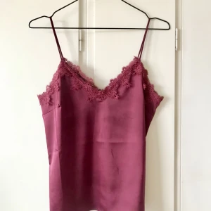  - Superfin gammelrosa topp i semiglansigt tyg med söta spetsdetaljer. Säljes pga dubbelköp, så snygg till ett par svarta vida byxor på fest! 