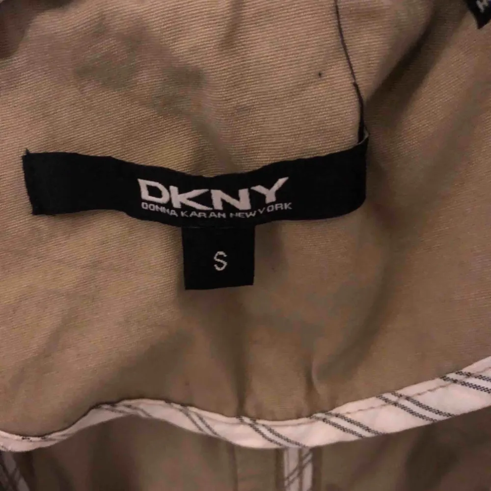 Säljer min DKNY kappa, (äkta) använd fåtal gånger. Har ett band runt midjan som går att knyta samt knappar. Färgen är lite åt det mörkare beige hållet.  . Jackor.