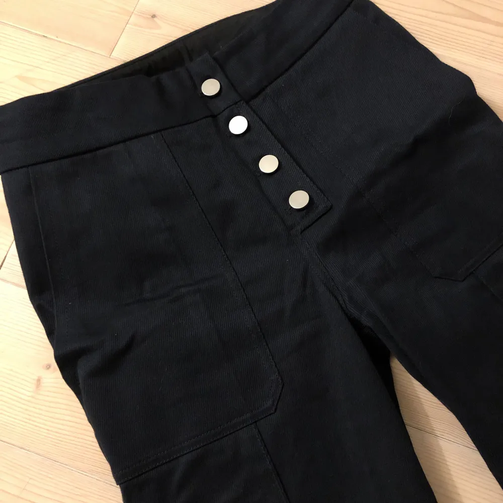 Mörkblå byxor med struktur från H&M Studio. Silverknappar, fickor utsvängda ben med slits på sidorna. Sparsamt använda.. Jeans & Byxor.
