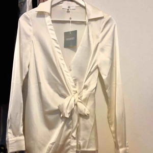  - Vit blus med knappar och knytning