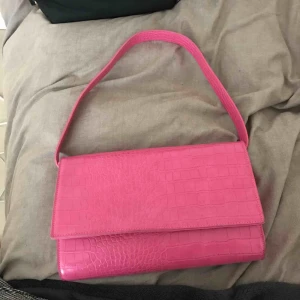  - rosa väska i ormskinnsimitation, storlek 28 cm i bred och 19 cm i höjd. Två innerfickor utan dragkedja och en stor innerficka med dragkedja. perfekt skick!