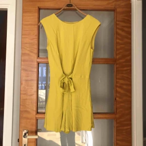  - Gul shortsdress med delvis öppen rygg. Använd ett fåtal gånger.