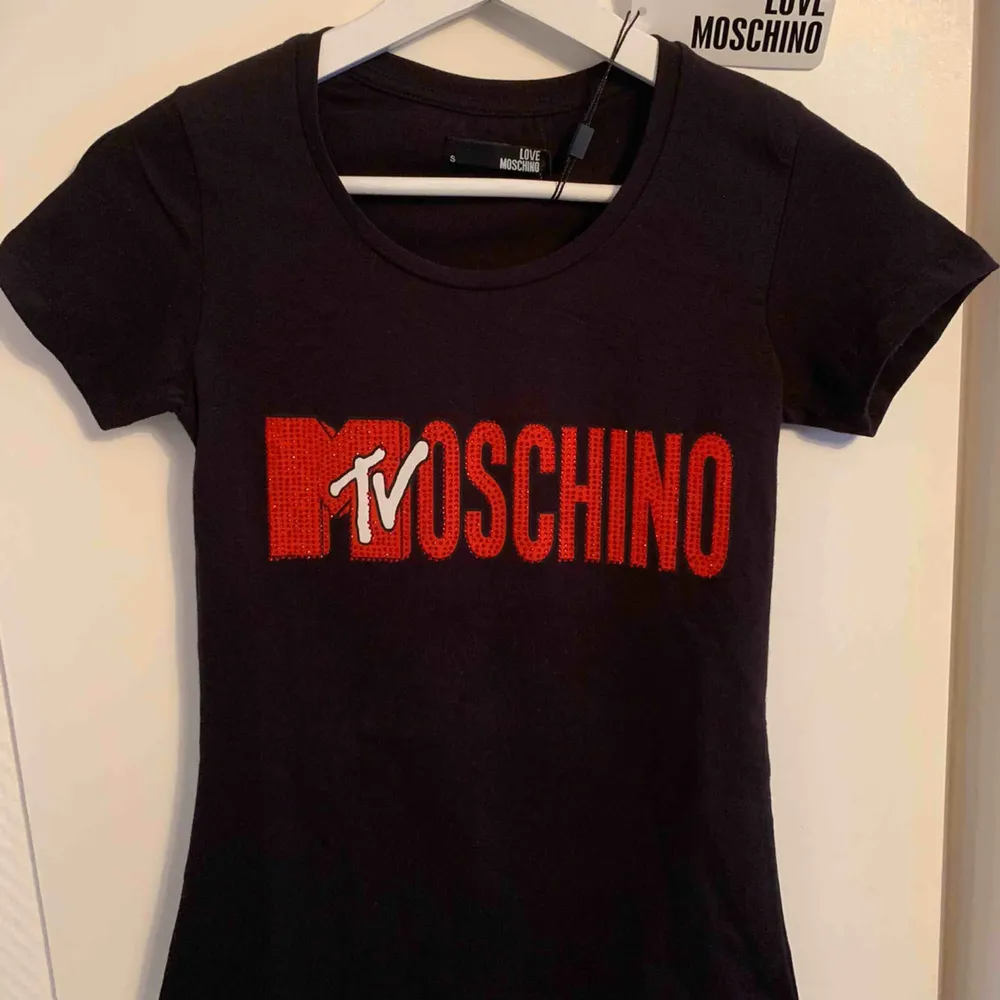 Oanvänd märkes t-shirt från MOSCHINO för tjejer Storlek: S  —— OBS: KÖPAREN STÅ FÖR FRAKTEN! - Frakt med spårnummer kostar 63kr. T-shirts.