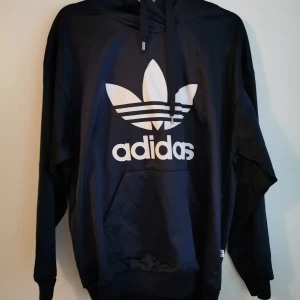 Adidas hoodie  - Glansigt material, stl 38, mörkblå. I mycket fint skick. 