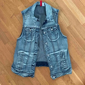  - Jeansväst från H&M med nitar vid axlarna. Väldigt fint skick då den inte är mycket använd. Ser något skrynklig ut vid kragen för den har varit nerpackad ett tag.   Köparen står för ev frakt. 