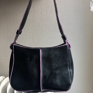 Liten handväska med lita detlajer - Svart väska med lila detaljer och foder. Köpt på second hand. 