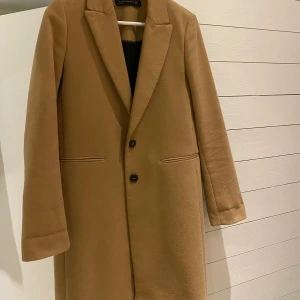 Beige kappa - Snygg beige kappa från zara i kamel/beige färg. Kappan är använd men i väldigt bra skick. Passar perfekt nu till hösten 🍂 Skickar gärna om köparen står för frakt. 