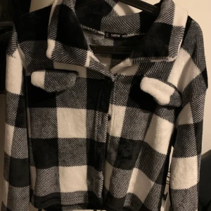 Flanell kofta/skjorta - En jätte mysig typ teddy material kort kofta/jacka/skjorta i svart vit flanell. Betalning sker via swish och köparen står för ev frakt! (Ca 60kr)
