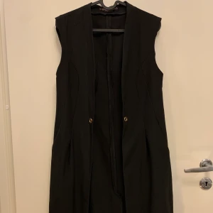 Väst  - Lång svart väst, står ingen storlek men jag bär S-M och den passar bra :) Använd 3-4ggr max. Köpare står för frakt skickas spårbart 63kr eller möts upp i Malmö, startbud 20kr
